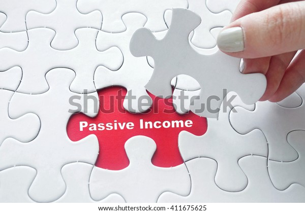 Close up of girl's hand placing the last jigsaw puzzle piece with word Passive Income