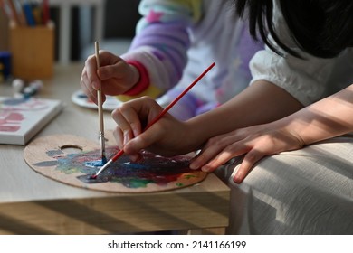 Close Up Girls Sitting Together, Mixing Colors On A Color Palettes Using Paint Brushes A, For Art, Education, Home And Family Concept.