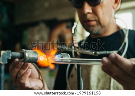 Close up of glass blower working with flame. Concept of handmade, high quality, artisan. Production of neon tubes. gas burner. detail of craft and craftsmanship. melt blown