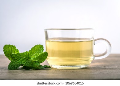 Close up glass cup of mint tea with green fresh peppermint leaves , relaxation and healthy drink