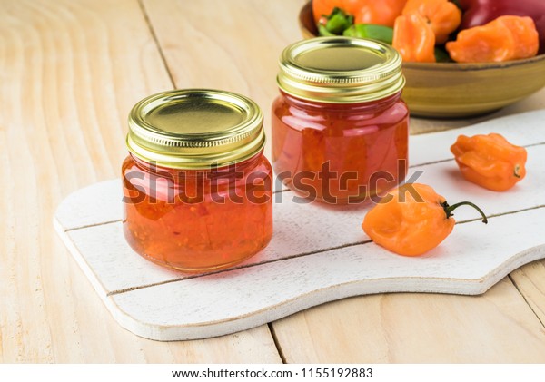 Close up of glass jars with habanero jelly on\
a wooden background.
