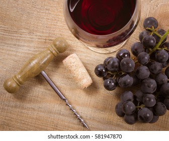 Close up - glass of red wine with a sprig of grapes on a wooden background.