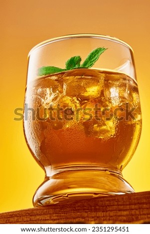 Close up glass of refreshing iced tea with ice cubes and mint leaves. Studio shot from a low angle. Vertical frame.