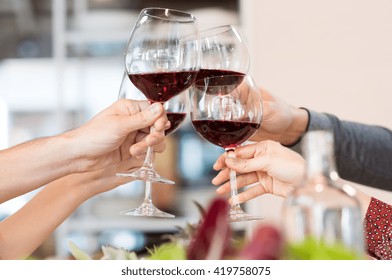 Close Up Of Glasses Raising A Toast At Lunch. Closeup Of Friends Toasting Glasses Of Red Wine In A Party. Group Of Friends A Toast To The Cheers Of Red Wine At Restaurant.
