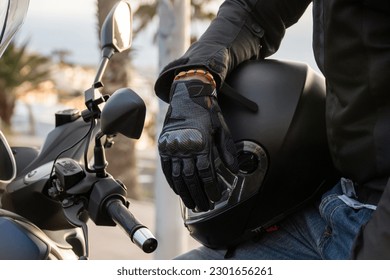 Close up of a gloved biker's hand resting on his helmet. Road safety concept - Shutterstock ID 2301656261