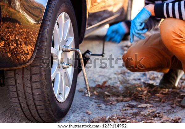 close up of a gloved hand changing tires of car.\
Change the car wheel in the tire, replace the winter tires for cars\
in the winter.