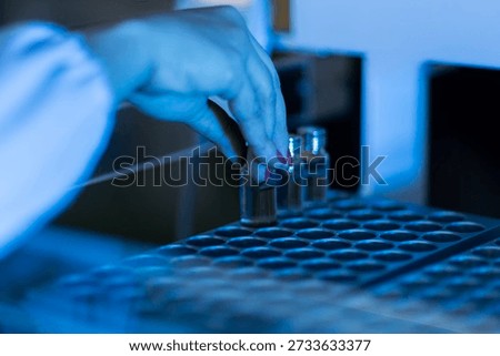 Close up of a gloved hand placing sample tubes into a laboratory centrifuge. The image represents science, biotechnology, research, and laboratory equipment.