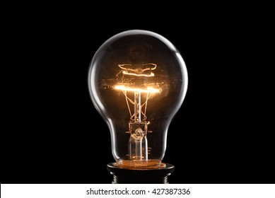 Close up glowing vintage light bulb. Isolated on black background