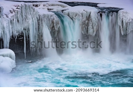 Close up of Godafoss Waterfall in Iceland, partially frozen in winter. Long exposure motion blur