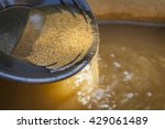Close up of gold panning pan with sifting sand.  Shallow depth of field with focus on sand flowing over edge of pan into water.