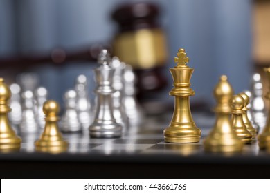 Close Up Golden Chess Pieces With Blurry Judge Gravel And Law Book Background.