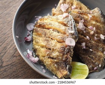 close up golden crispy deep-fried snakeskin gourami fish with fresh shallot and lime