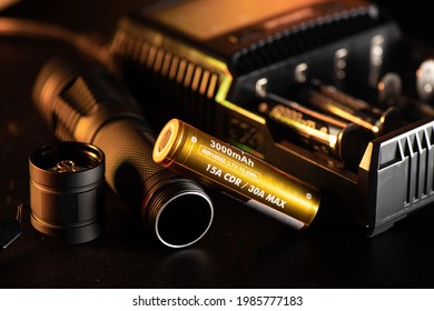 Close up the golden INR18650 3.7V rechargeable battery with charger. INR18650 battery is Lithium nickel rechargeable battery with size 18mm by 65mm.
