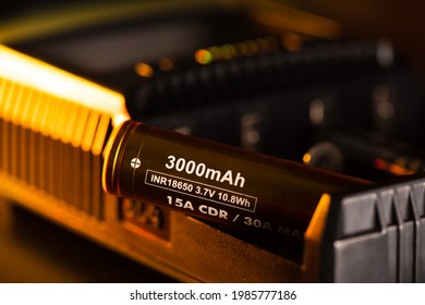 Close up the golden INR18650 3.7V rechargeable battery with charger. INR18650 battery is Lithium nickel rechargeable battery with size 18mm by 65mm.