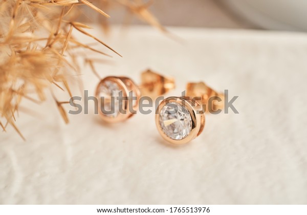 Close up golden stud earrings, with white\
crystals and diamonds. Beautiful earrings on white background.\
Women accessories