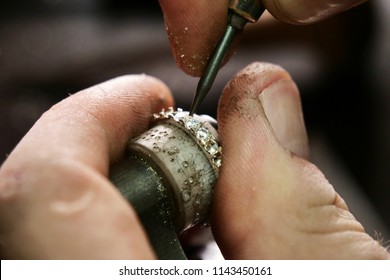 Close up of a goldsmith's hand making a gold or silver ring or a diamond using goldsmith's tools. For this work it takes precision and patience. Concept of: tradition, luxury, jewelry.