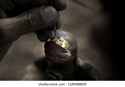 Close up of a goldsmith's hand making a gold or silver ring or a diamond using goldsmith's tools. For this work it takes precision and patience. Concept of: tradition, luxury, jewelry.