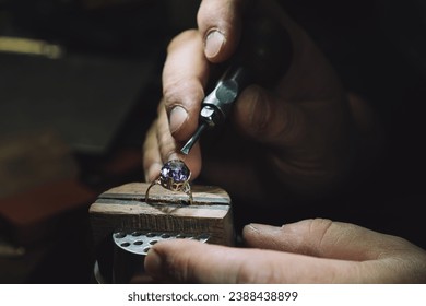 Close up of a goldsmith's hand making a gold ring with gem using goldsmith's tools. For this work it takes precision and patience. Concept of: tradition, luxury, jewelry. - Powered by Shutterstock