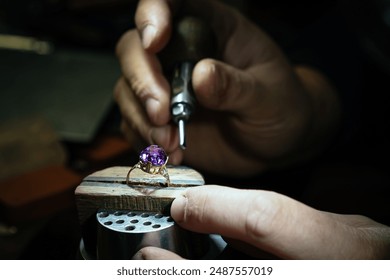 Close up of a goldsmith's hand making a gold or silver ring or a diamond using goldsmith's tools. For this work it takes precision and patience. Concept of: tradition, luxury, jewelry. - Powered by Shutterstock