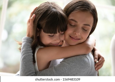 Close up gorgeous sisters different age hugging closed eyes enjoy moment of tenderness feels happy, mother and little daughter cuddling having strong bonds, adopted kid new mom reunification concept