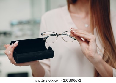 Close Up Of Gorgeous Young Woman Smiling Picking And Choosing Glasses At The Optician Corner At The Shopping Mall. Happy Beautiful Woman Buying Eyewear Eyeglasses At The Optometrist.