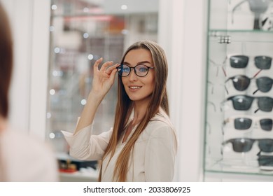 Close up of gorgeous young woman smiling picking and choosing glasses at the optician corner at the shopping mall. Happy beautiful woman buying eyewear eyeglasses at the optometrist. - Powered by Shutterstock