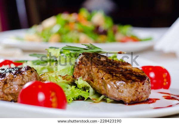 Close\
up Gourmet Main Course - Grilled Tender Juicy Meat with Veggies and\
Rosemary on White Plate. A Rich in Protein\
Recipe.