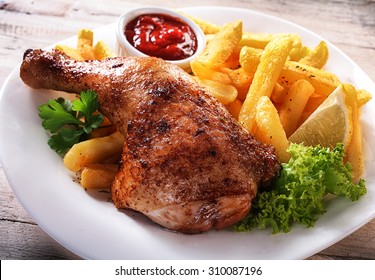 Close up Gourmet Tender Juicy Chicken and Fries Dish on a White Plate with Fresh Lettuce, Lemon and Sauce. - Powered by Shutterstock