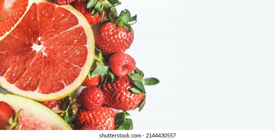 Close Up Of Grapefruit Halve With Red Fruits And Berries: Strawberries And Raspberries On White Background. Healthy Delicious Summer Food. Border. Top View With Copy Space.