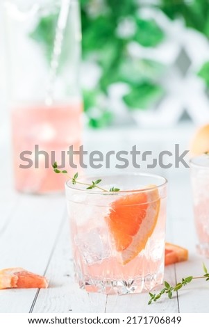 Close up of grapefruit spritzer with slices of grapefruit and thyme.