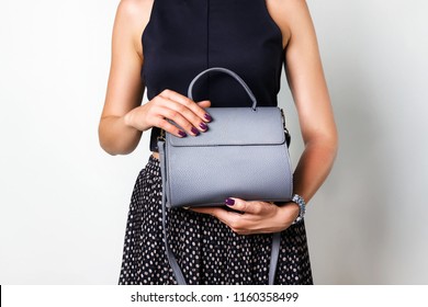 Close Up Of Gray Leather Handbag In Hand Of Stylish Woman, Studio Shot On Gray Background. Female Fashion And Accessories.