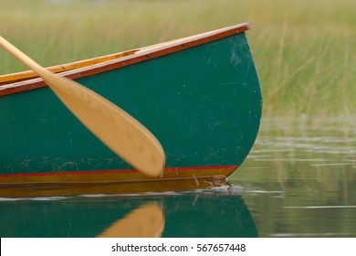 Close Up Of A Green Canoe In The Water With Its Paddle Splashing Water