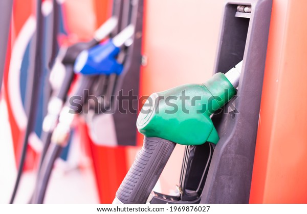 Close up green fuel nozzle\
on tank of gas station in commercial gas station to filling power\
oil energy into car for transportation without copy space in\
frame.