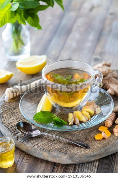 Close up of green tea with ginger, turmeric and\
honey on a wooden board.