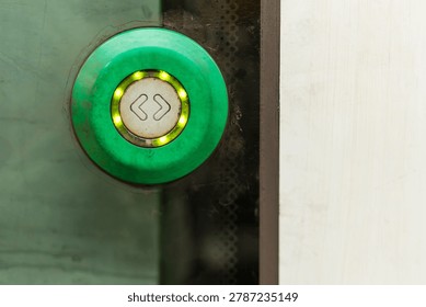 Close up of a green train door button outside a modern metro carriage. The image shows passenger interface, public transport details, access control, urban commuting, safety design, and everyday travel infrastructure.