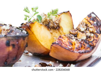 Close Up Of Grilled Peaches With Blue Cheese And A Balsamic Reduction On A White Background