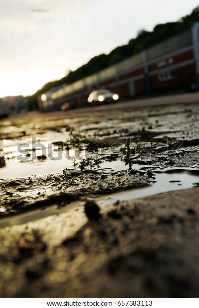 A close up from the ground in the port of\
Hamburg with a puddle in the\
foreground