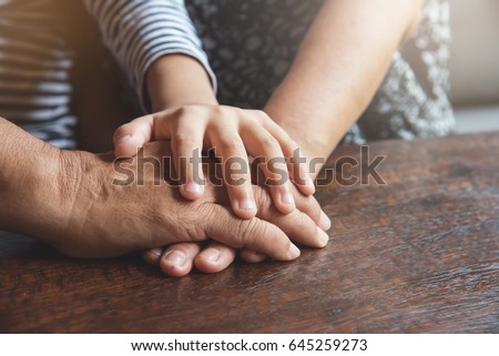 Close up of Group of Asian Elderly and kid join hands or stacking on old wood table together. Teamwork, Partnership, support, unity, Power of family team concept.