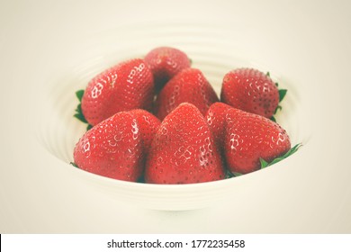 Close up a group of large ripe strawberries from an organic farm, red big size, freshness, and sweet fruit contained in the white bowl by isolated and vintage style on white background.