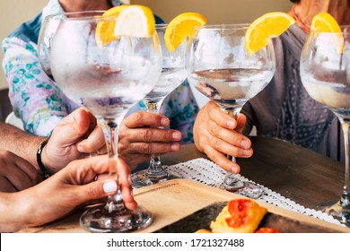 Close up of group of people friends or family celebrate together drinking cocktails or wines from big glass - home or restaurant event close up concept with caucasian hands and beverages