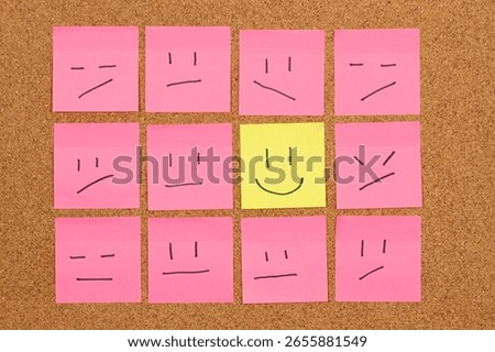 Close up to a group of sticky notes representing hapiness surrounded with a lot of depressive faces over a cork background