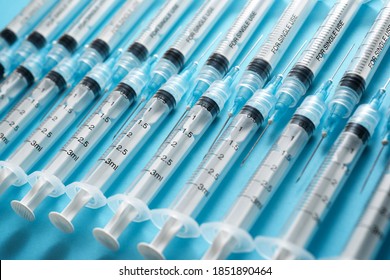 Close up of a group of syringes on a blue table.