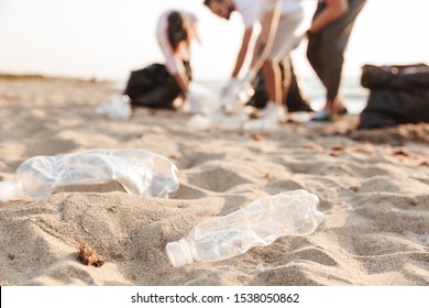 Close up of a group of young cheerful friends volunteers cleaning beach from plastic - Powered by Shutterstock