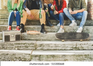 Close Up Of Group Of Young People Hands Toasting Beer And Having Fun Outdoor - Fashion Buddies Sitting In Staircase Socializing - Concept Of Relaxation With Friends - Focus On Left Man Hands 