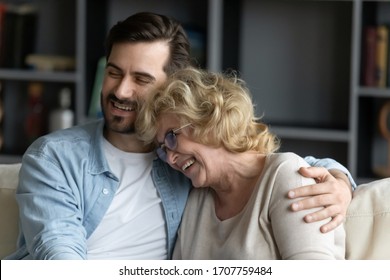 Close Up Of Grown Up Child Son Hugs Elderly Mother Family Sit On Couch Enjoy Talk Funny Conversation Laughing, Remember Life, Share Positive News Feels Happy Spend Time Together, Family Bonds Concept