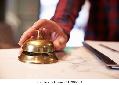 Close Up Of Guest's Hand On Hotel Reception Bell