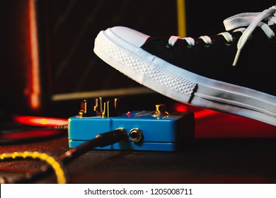 Close up of guitar player foot pressing pedal. Musician uses music effect loop machine. Man in trendy sneakers, his foot playing at stage during concert. Macro view - Powered by Shutterstock