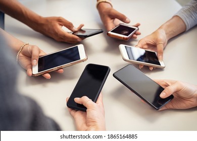 Close up of guys and girls hands in circle using smart phone. High angle view of multiple hands holding mobile phone with empty screen. Group of multi cultural friends using smartphone together. - Shutterstock ID 1865164885
