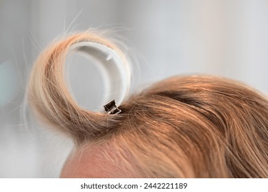 Close up of a hair roller to create bangs or curly hair on a blonde woman