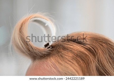 Close up of a hair roller to create bangs or curly hair on a blonde woman